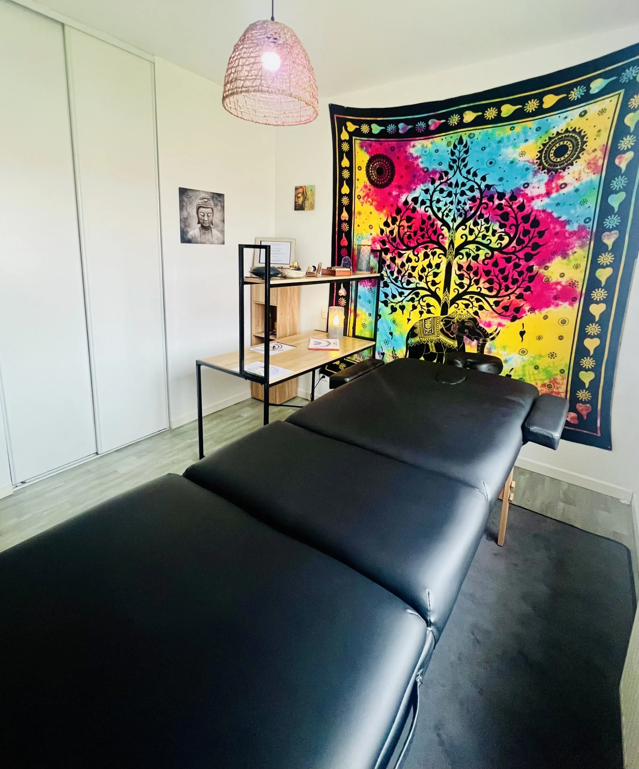 espace soin holistique reiki massage.webp 2 scaled - Reiki près de Cholet & Nantes Espace de soin décoré d’un tissu mural coloré avec une table de massage et des éléments spirituels