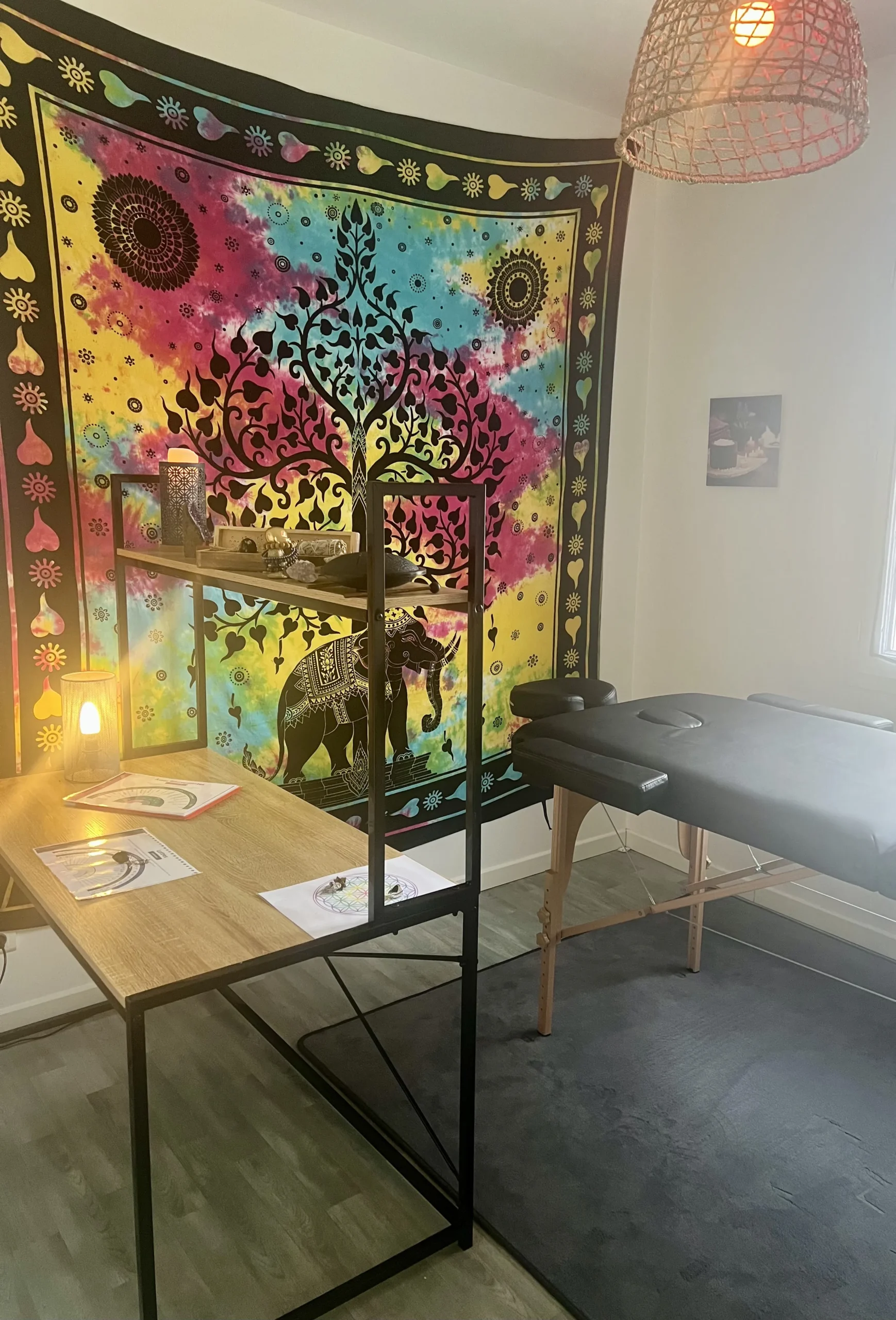 espace soin zen reiki massage holistique.webp scaled - Reiki près de Cholet & Nantes Salle de soin équipée d’une table de massage et décorée d’un tissu mural coloré représentant l’arbre de vie